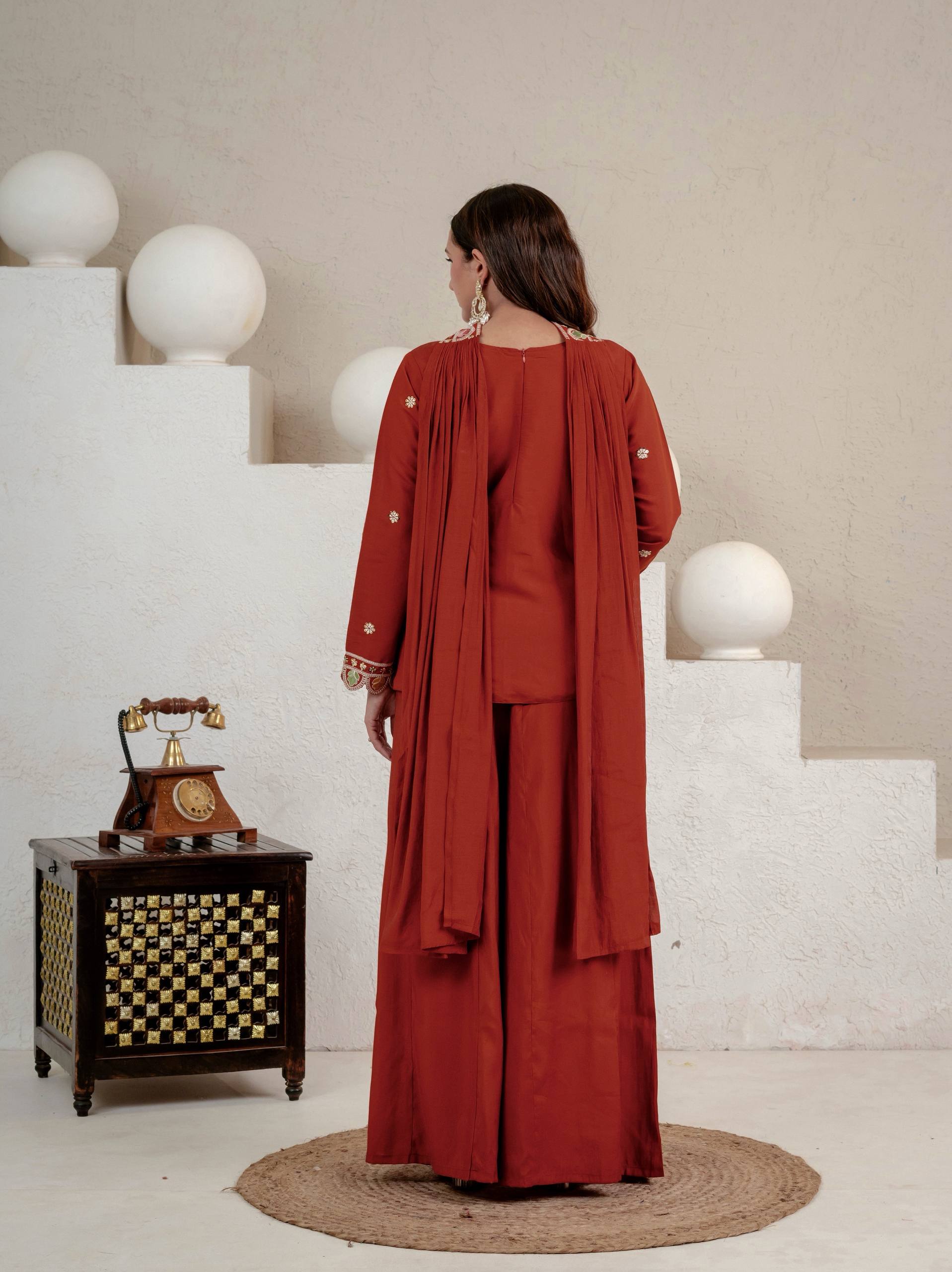 Resplendent Rust Orange Peplum Kurti and Flared Palazzo Suit Set Adorned with Intricate Multicolored Floral Embroidery, Sequin Accents, and Ornate Scalloped Borders